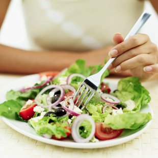 A woman eats a healthy salad.